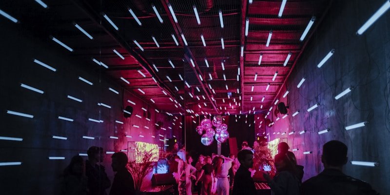 Tunnel of neon light bars above a packed dance floor