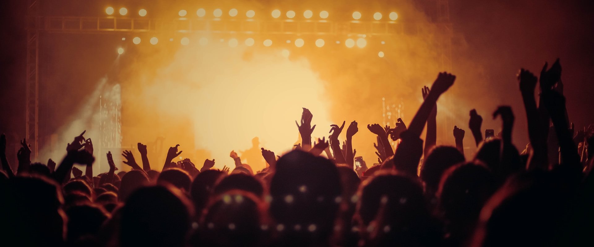Crowd with raised hands under golden stage lights